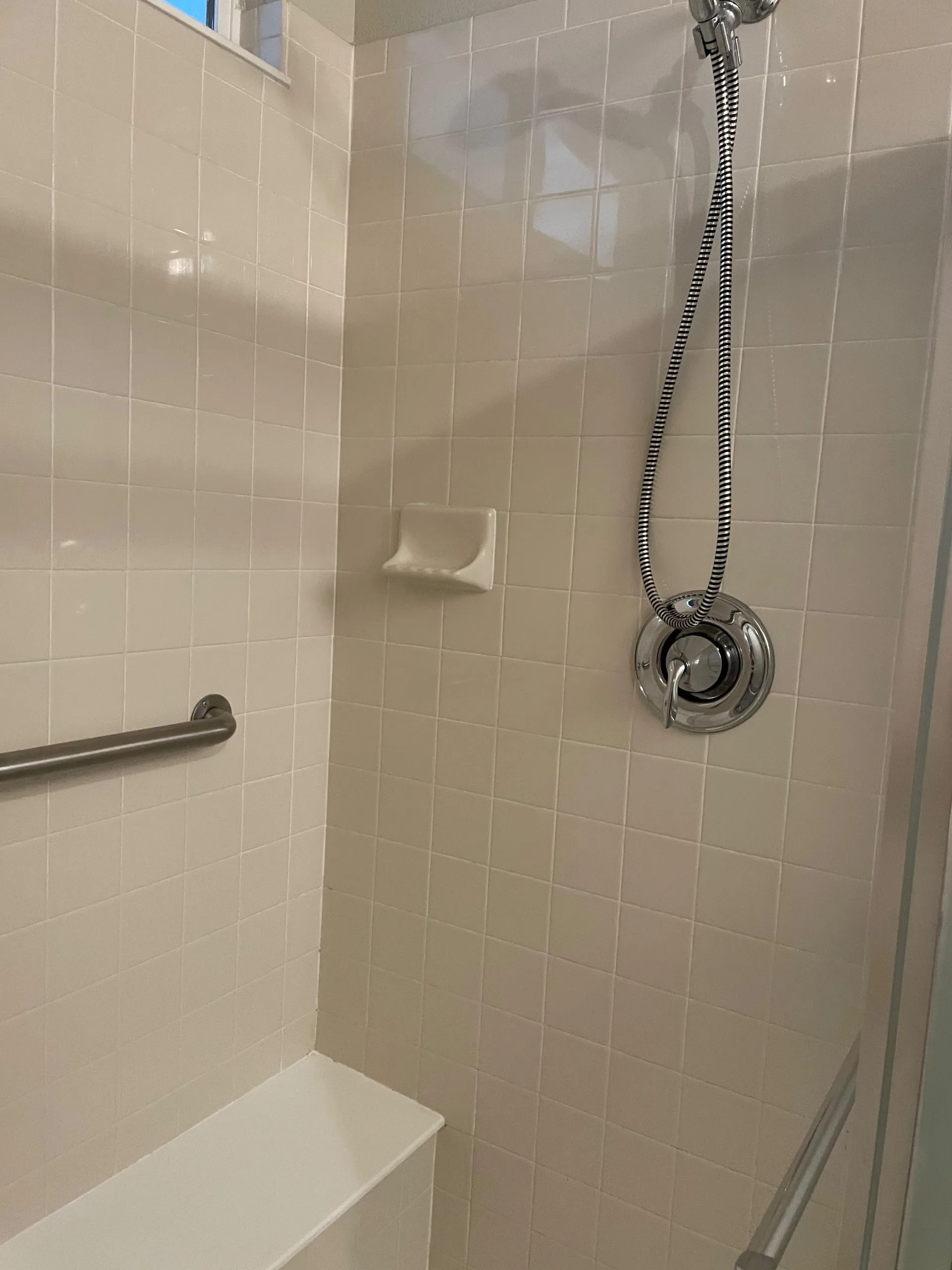 Sparkling white-tiled shower with polished chrome fixtures after a deep clean